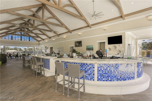 bar featuring hardwood / wood-style floors, light stone counters, high vaulted ceiling, and beam ceiling