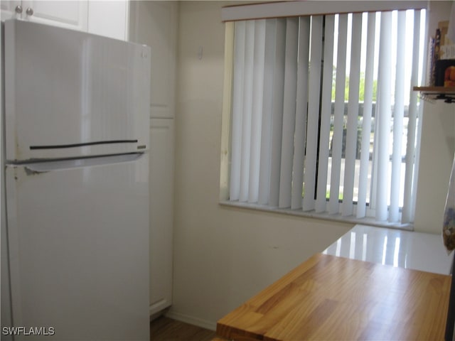 kitchen with white refrigerator and white cabinetry