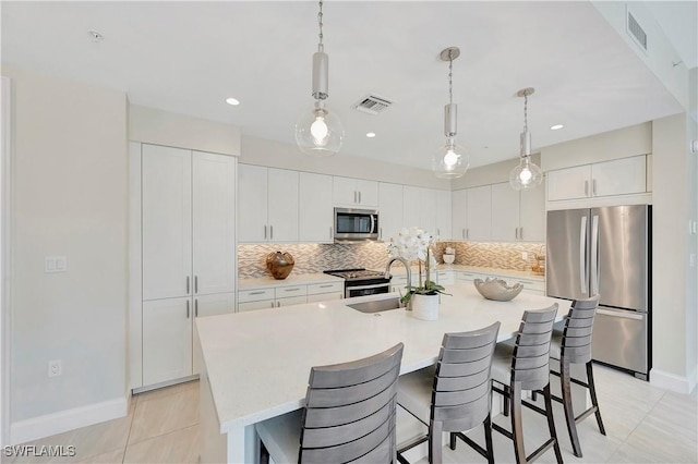 1111 Central Ave Unit 211, Naples, FL 34102 - kitchen with stainless steel appliances, backsplash, a kitchen bar, an island with sink, and recessed lighting