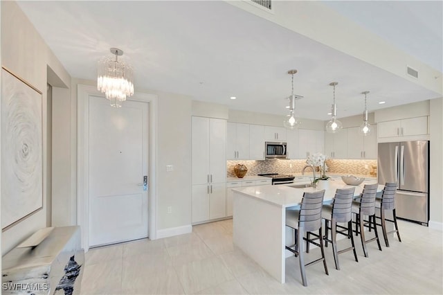 kitchen with pendant lighting, decorative backsplash, a center island with sink, and stainless steel appliances