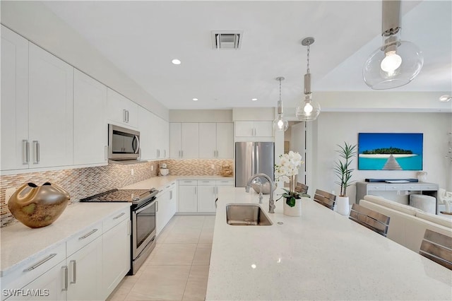 kitchen with decorative backsplash, stainless steel appliances, sink, decorative light fixtures, and white cabinetry