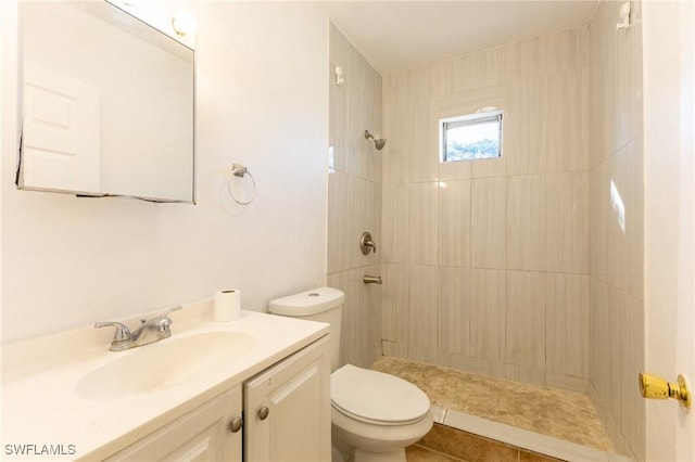 bathroom with tile patterned floors, vanity, toilet, and a tile shower