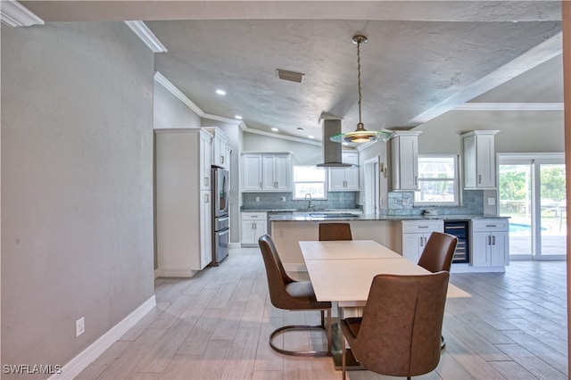 dining area with a wealth of natural light, ornamental molding, beverage cooler, and light wood-type flooring