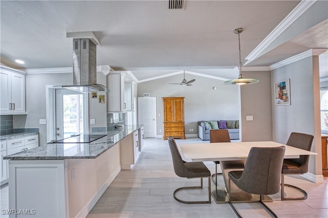 kitchen featuring white cabinetry, crown molding, vaulted ceiling, island range hood, and light wood-type flooring