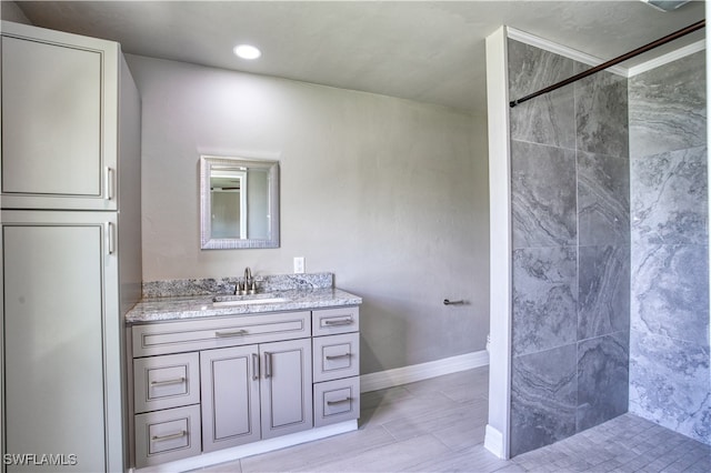 bathroom featuring hardwood / wood-style floors, vanity, and tiled shower