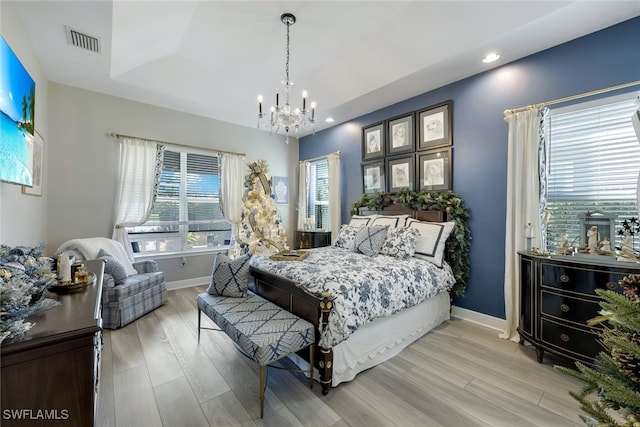 bedroom featuring a chandelier, light hardwood / wood-style flooring, and multiple windows