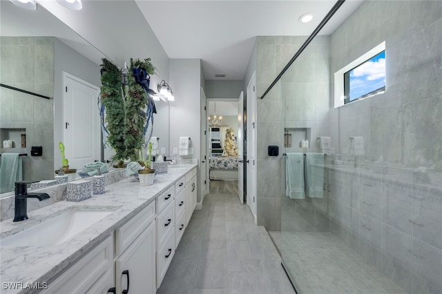 bathroom featuring tile patterned floors, vanity, a shower with shower door, and tile walls