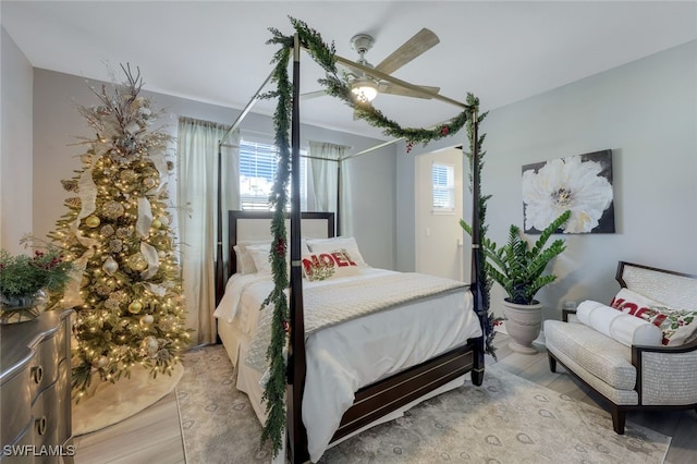 bedroom featuring hardwood / wood-style floors, ceiling fan, and multiple windows