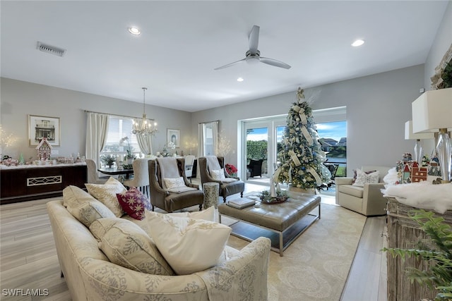 living room featuring ceiling fan with notable chandelier and light hardwood / wood-style floors