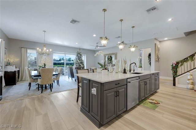 kitchen with a kitchen island with sink, light hardwood / wood-style flooring, stainless steel dishwasher, and ceiling fan with notable chandelier