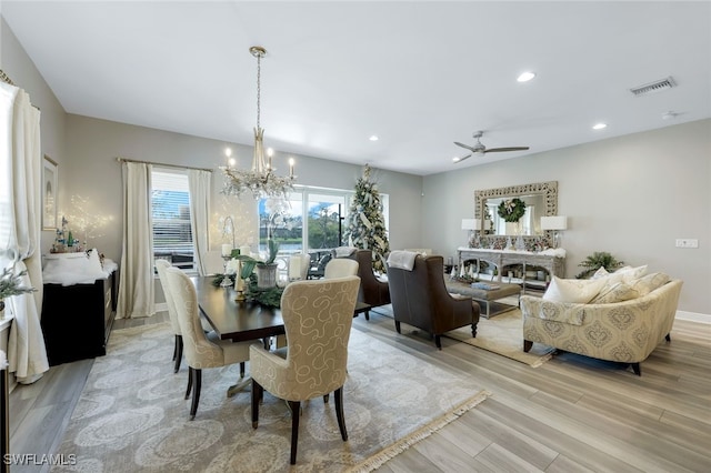 dining room with ceiling fan with notable chandelier and light wood-type flooring