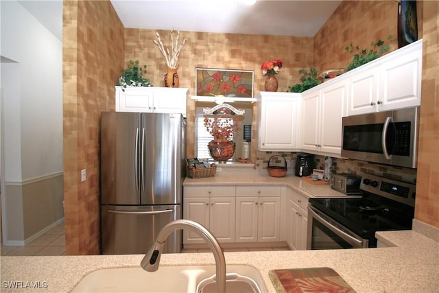 kitchen featuring sink, light tile patterned floors, tasteful backsplash, white cabinets, and appliances with stainless steel finishes