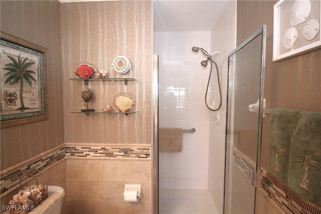 bathroom with toilet, a shower with door, and tile walls