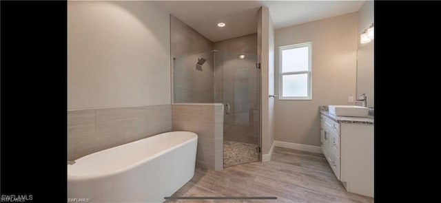 bathroom with vanity, wood-type flooring, and plus walk in shower