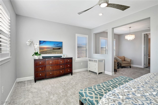 bedroom featuring light carpet, baseboards, and ceiling fan with notable chandelier