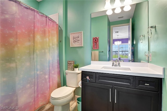 bathroom featuring vanity, toilet, and a notable chandelier