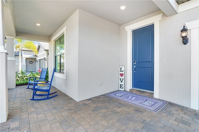 doorway to property with a porch and stucco siding