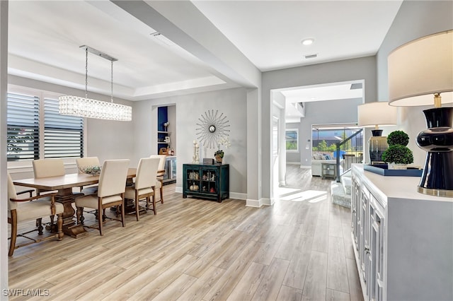 dining room with a raised ceiling and light hardwood / wood-style flooring