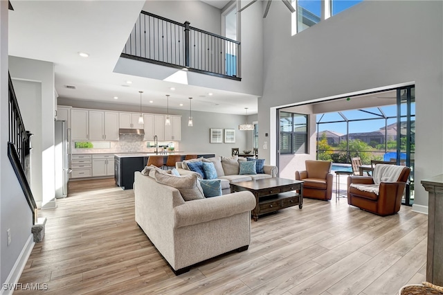 living room with a mountain view, a high ceiling, light hardwood / wood-style floors, and sink