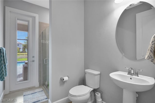 bathroom featuring toilet, a shower stall, baseboards, and a sink