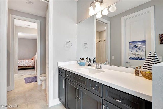 ensuite bathroom with baseboards, toilet, ensuite bath, tile patterned floors, and vanity