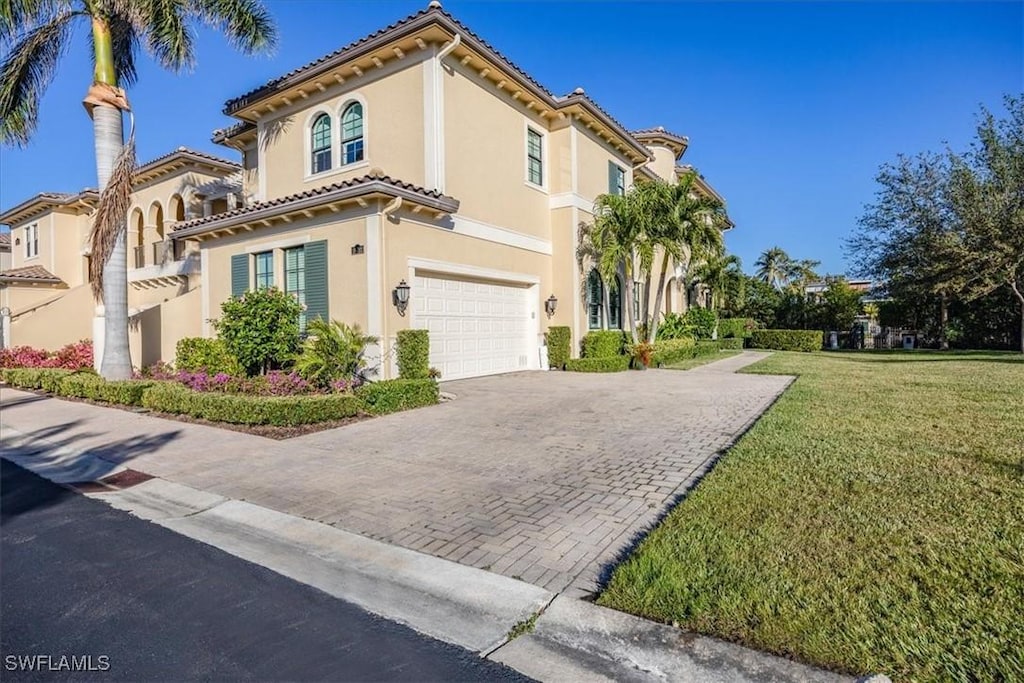 mediterranean / spanish-style home featuring a front lawn and a garage