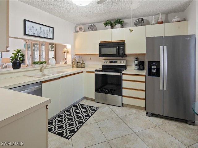 kitchen with sink, a textured ceiling, light tile patterned floors, appliances with stainless steel finishes, and kitchen peninsula