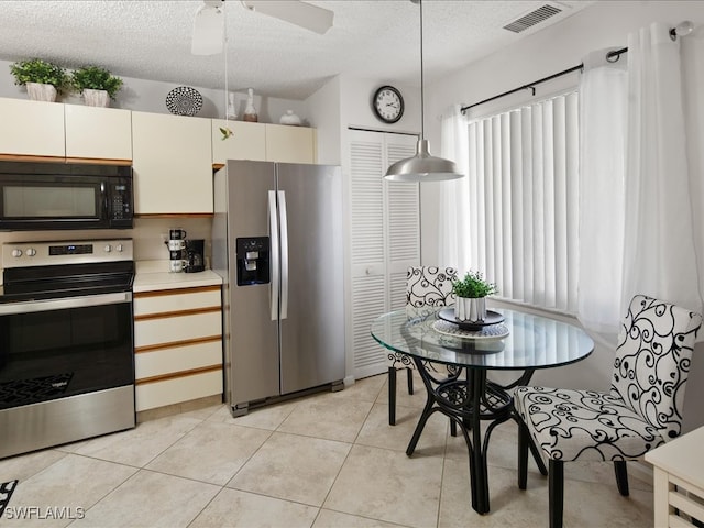 kitchen with appliances with stainless steel finishes, pendant lighting, light tile patterned floors, ceiling fan, and a textured ceiling