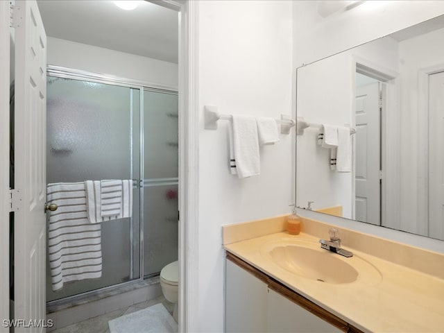 bathroom featuring a shower with door, vanity, tile patterned floors, and toilet