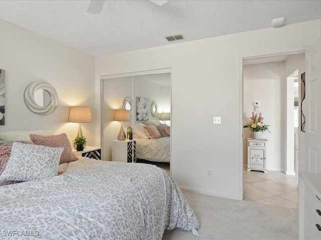 bedroom with ceiling fan, carpet flooring, a textured ceiling, and a closet