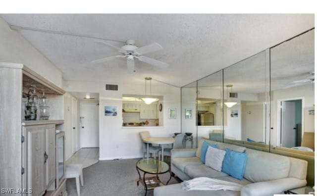 carpeted living room featuring ceiling fan and a textured ceiling