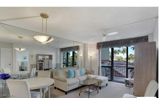 living room featuring carpet flooring, a textured ceiling, and ceiling fan