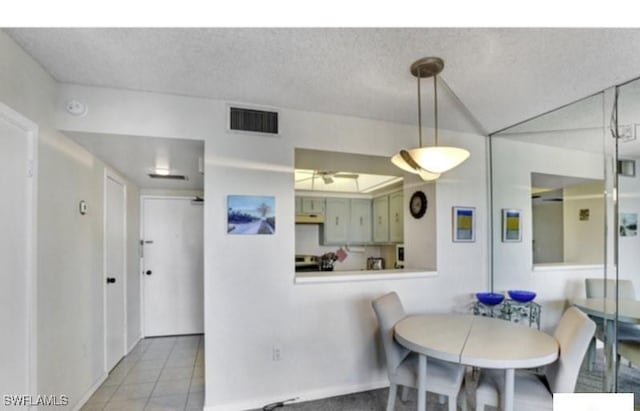 tiled dining space with ceiling fan and a textured ceiling