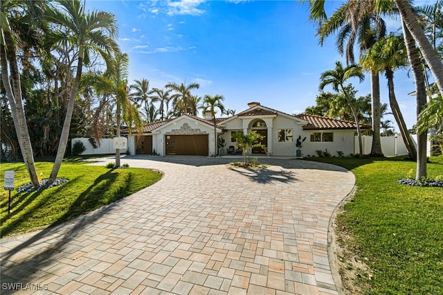 mediterranean / spanish home featuring a front yard and a garage