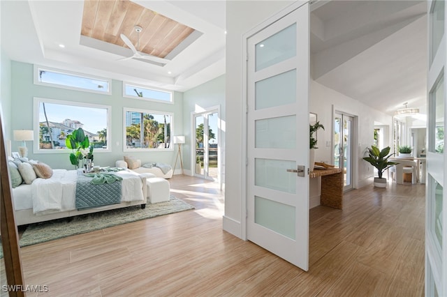 bedroom with a raised ceiling, wood ceiling, light hardwood / wood-style floors, and a high ceiling