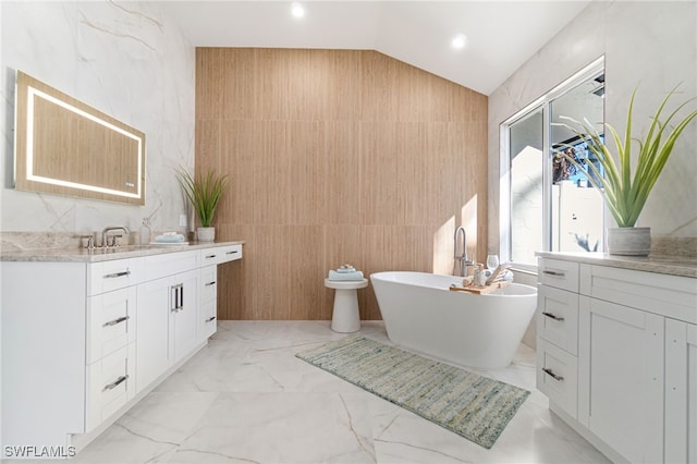 bathroom featuring a tub to relax in, tile walls, vanity, and lofted ceiling