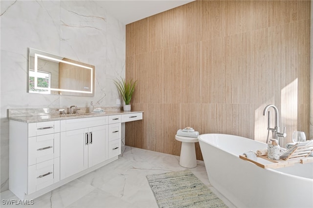 bathroom with vanity, a tub to relax in, and tile walls