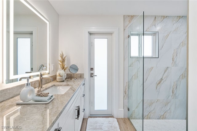 bathroom with vanity, wood-type flooring, and tiled shower