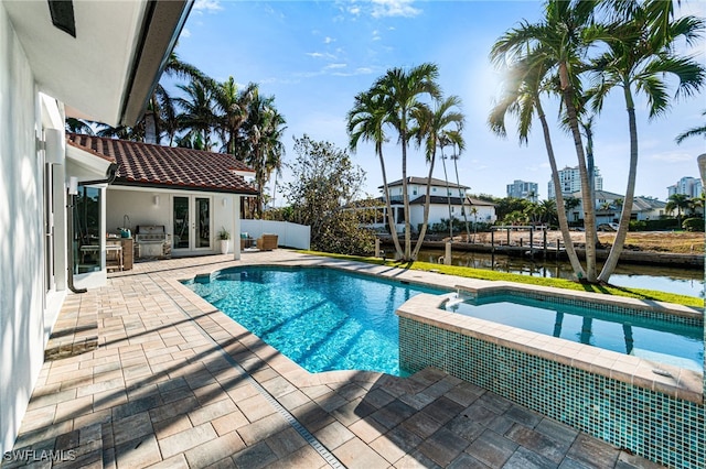 view of swimming pool with area for grilling, a water view, exterior kitchen, and a patio area