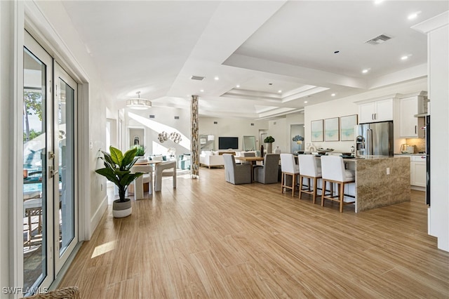 living room featuring a tray ceiling and light hardwood / wood-style flooring