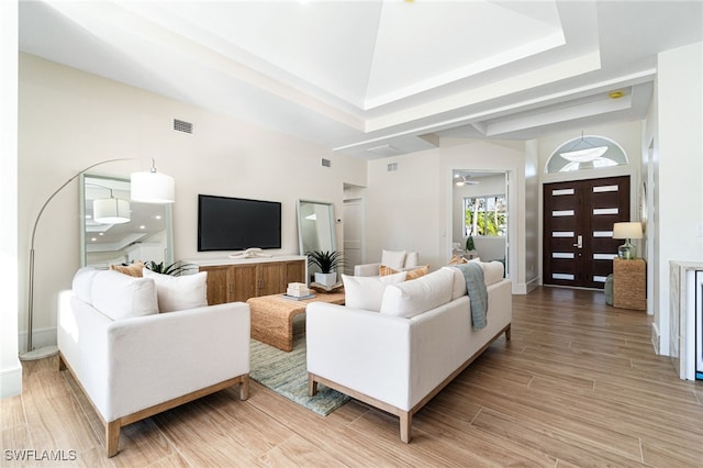 living room with a raised ceiling, ceiling fan, and hardwood / wood-style floors