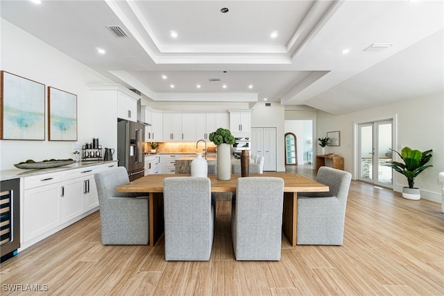 dining space featuring light hardwood / wood-style floors and a tray ceiling