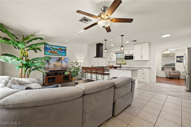 living room featuring a textured ceiling, ceiling fan, and light tile patterned flooring