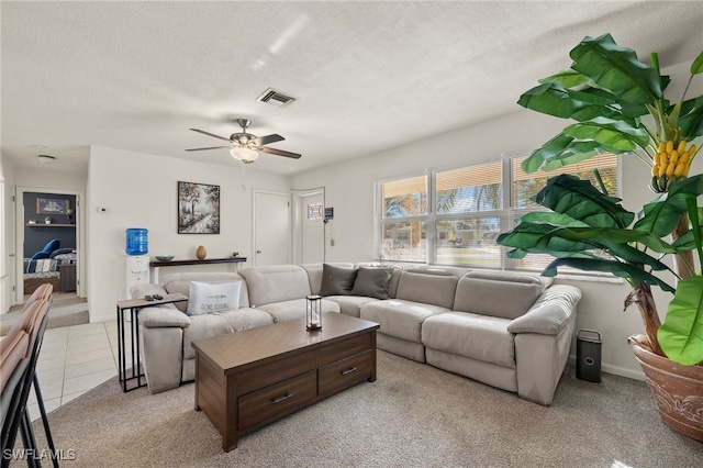 living room with ceiling fan, light colored carpet, and a textured ceiling