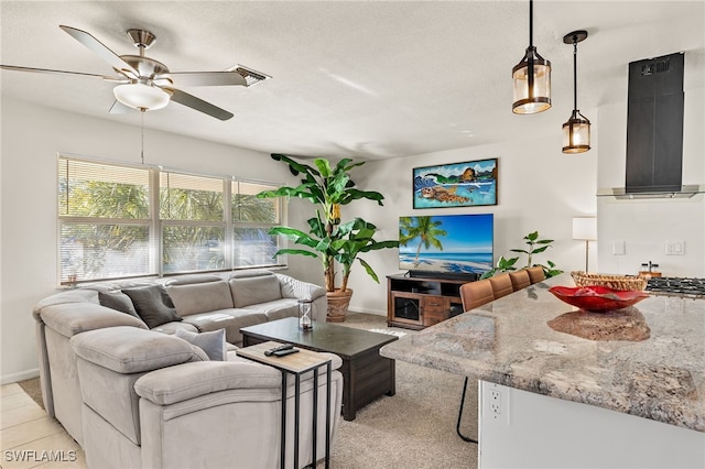 living room with ceiling fan, light colored carpet, and a textured ceiling