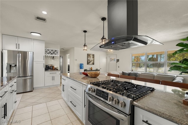 kitchen featuring white cabinets, light tile patterned floors, appliances with stainless steel finishes, island range hood, and light stone counters