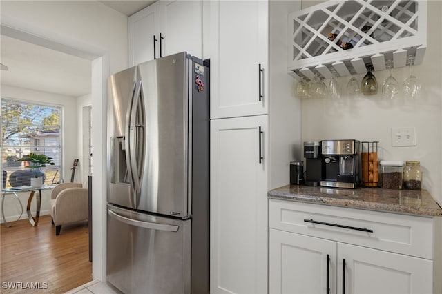 kitchen featuring light hardwood / wood-style floors, dark stone countertops, white cabinetry, and stainless steel refrigerator with ice dispenser