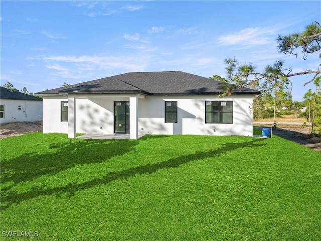 back of property featuring a yard, roof with shingles, and stucco siding