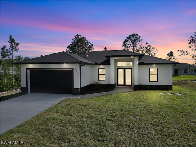 view of front facade featuring a garage, a lawn, concrete driveway, and stucco siding