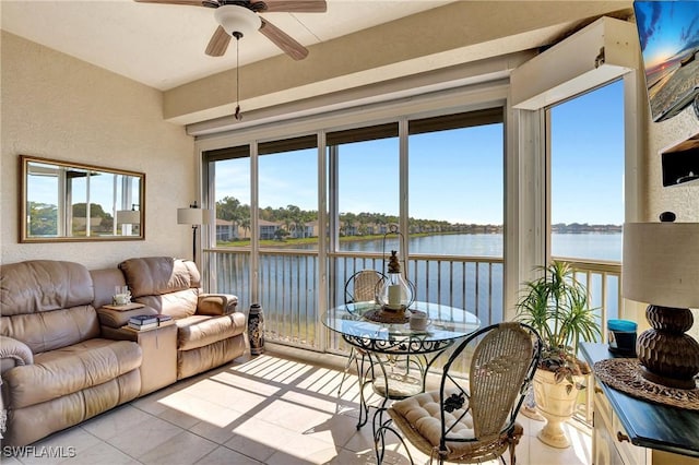 sunroom featuring ceiling fan and a water view